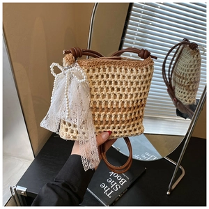 Détail du sac seau tissé avec anse en cuir et nœud décoratif en dentelle et perles