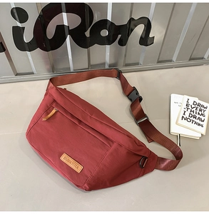 Détail du sac bandoulière en nylon bordeaux avec sangle marron et tirette en cuir