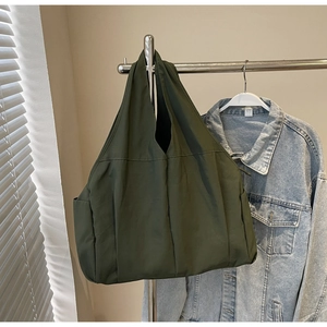 Détail d'un grand sac fourre-tout en nylon vert foncé avec poche latérale sur un cintre