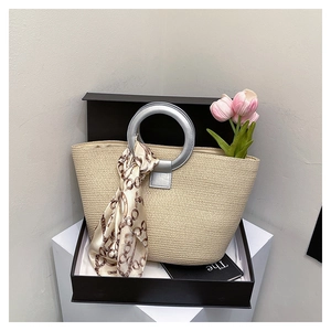 Close-up of beige woven tote bag in a gift box with a metal handle and silk scarf