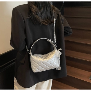 Quilted silver hobo bag with chain strap and lace pearl charm shown in a lifestyle setting