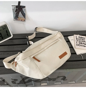 Détail du sac à bandoulière en toile crème avec boucle réglable et étiquette en cuir