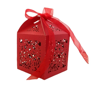 Detail of red laser-cut candy box featuring floral hollow patterns and organza ribbon
