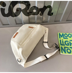 Détail du sac bandoulière blanc cassé avec étiquette en cuir et sangle réglable
