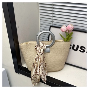 Detail of beige woven straw tote with silver round handle and floral silk scarf accessory