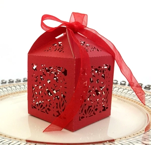Macro view of red laser-cut candy box with floral pattern and organza ribbon decoration