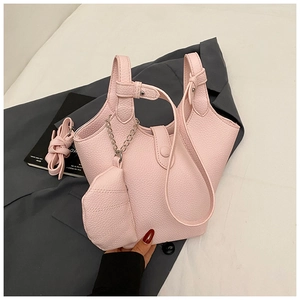 Close-up of pink litchi grain leather bucket bag with silver chain and mini coin purse charm