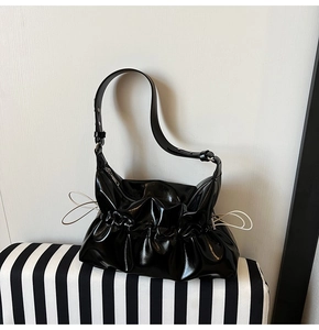Vue détaillée du sac plissé en cuir verni noir avec des accents de cordon blanc