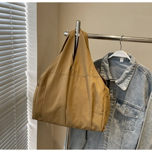 Détail d'un sac cabas en toile kaki suspendu avec une large bandoulière de confort
