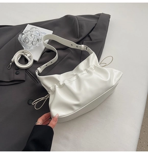 Détail d'un sac nuage plissé blanc sur blazer gris avec bandoulière réglable