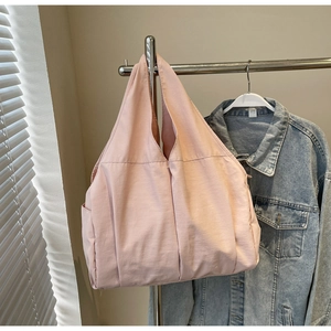 Vue détaillée d'un sac cabas en tissu rose avec poches latérales sur support métal