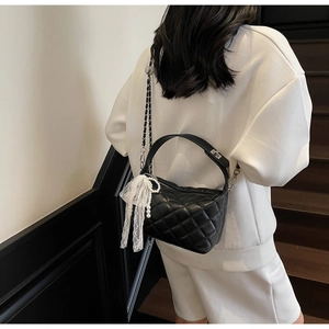 Quilted crossbody bag with lace bow and pearl charm detail shown on a model