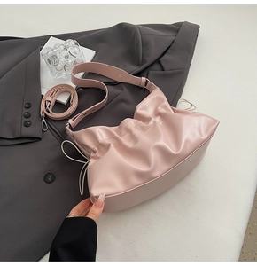 Détail du sac cabas plissé rose avec bandoulières réglables sur un blazer gris foncé