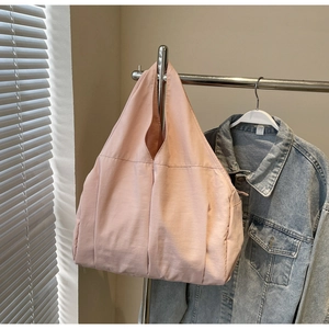 Détail latéral d'un grand sac cabas rose avec poches pratiques et plis élégants