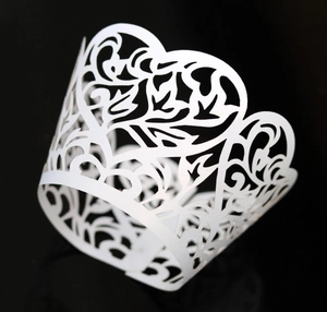 Close-up of white laser-cut vine cupcake wrappers with intricate floral patterns