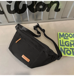 Vue détaillée du sac de poitrine en nylon noir avec un élégant patch logo en cuir marron