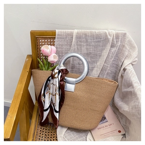 Close-up of woven tote bag with silver round handles and decorative printed silk scarf