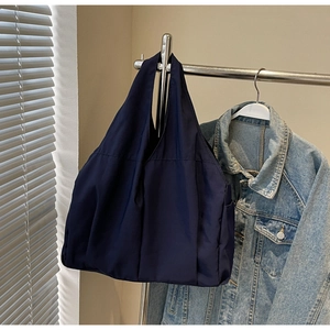 Détail d'un grand sac cabas bleu marine avec fond plissé sur un support métallique