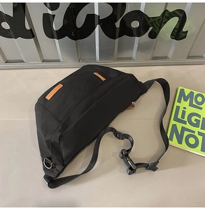 Détail du sac de poitrine en nylon noir imperméable avec étiquettes en cuir marron