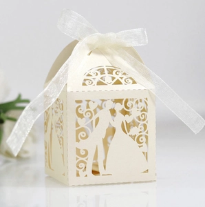Detail of laser cut hollow wedding favor box with bride groom silhouette and white ribbon