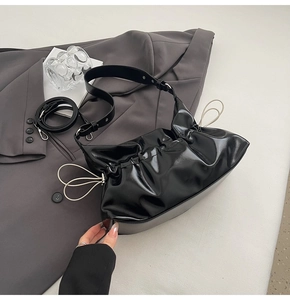 Détail du sac nuage noir plissé avec cordon crème et finition en cuir verni brillant