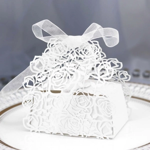 Close-up of laser-cut white favor box with rose patterns and sheer ribbon bow