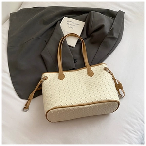Detail of woven beige tote bag with brown handles and adjustable side strap details
