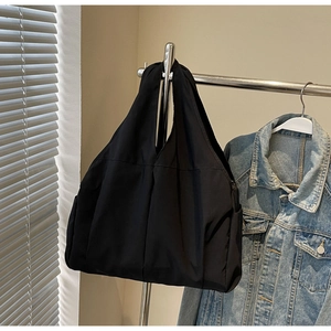 Vue détaillée du sac cabas en nylon noir léger avec large bandoulière et poche latérale