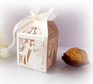 Macro detail of laser-cut hollow wedding favor box with ribbon and chocolate