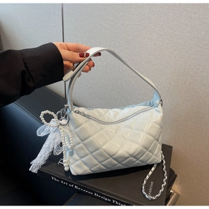 Detail of white quilted pillow bag featuring silver chain and pearl lace pendant