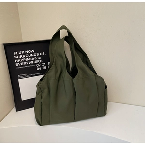 Détail du grand sac cabas en nylon vert olive avec poches latérales plissées sur socle