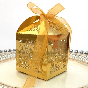 Close-up of laser-cut floral patterns on golden gift box with elegant organza ribbon