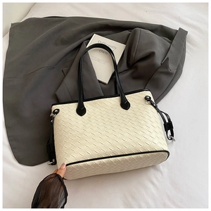 Detailed close-up of woven tote bag texture with black leather handle and side buckle