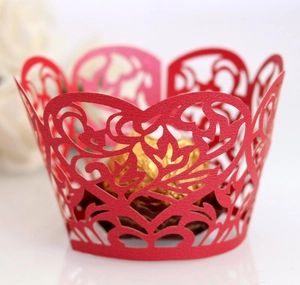 Detail of red laser-cut cupcake wrapper with heart patterns and gold chocolate decoration
