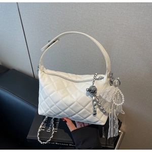 Detail of white quilted crossbody bag with silver chains, pearls and lace ribbon decor