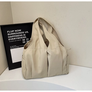 Gros plan sur un sac cabas en toile beige avec poches extérieures et larges bandoulières robustes