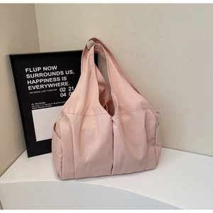 Vue détaillée du sac cabas rose avec plis verticaux et poches latérales pour le trajet