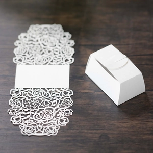 Detailed laser-cut white rose pattern gift box on dark wood surface background