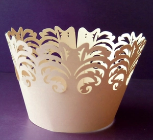 Detail of laser-cut cupcake wrappers with elegant cream floral lace crown pattern