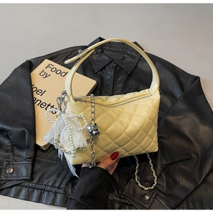 Close-up of cream quilted handbag featuring pearl lace bow and silver chain strap