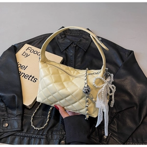 Detailed shot of quilted chain bag featuring pearl bow charms and lace ribbon accents
