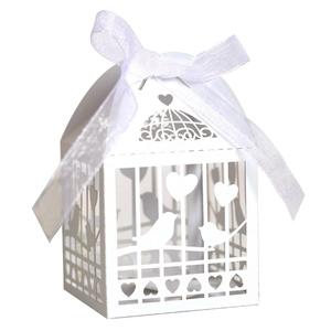 Detail of laser-cut white favor box with bird and heart patterns and silk ribbon bow