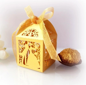 Close-up of laser-cut yellow wedding gift box with bride and groom silhouette and ribbon