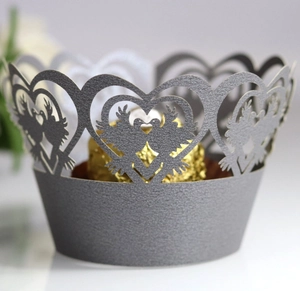 Macro detail of laser-cut silver pearl paper cupcake wrapper with heart and bird motifs