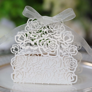 Detailed laser-cut white wedding favor box with elegant rose patterns and silver ribbon
