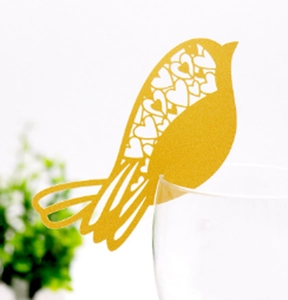 Golden laser-cut bird place cards for wine glasses with heart-shaped wing patterns