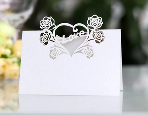 Detail view of white laser-cut wedding place card with rose and heart Love motifs