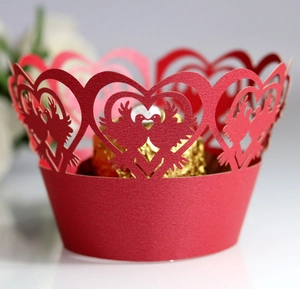 Detail of red laser-cut cupcake wrapper with heart and bird design for wedding decor