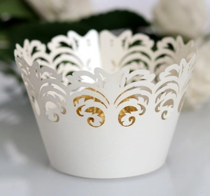 Laser-cut white cupcake wrappers with intricate filigree pattern for wedding decoration