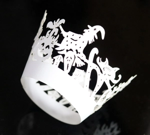 Close-up of laser-cut white paper cupcake wrappers featuring Halloween witch and pumpkin